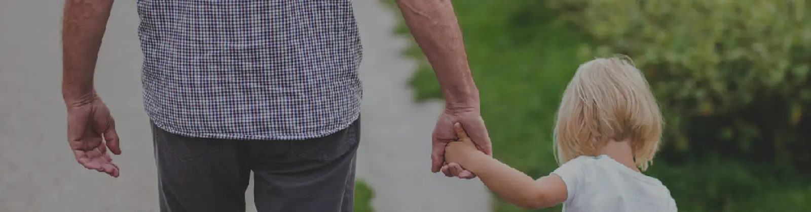 Un adulto mayor y una niña caminando de la mano